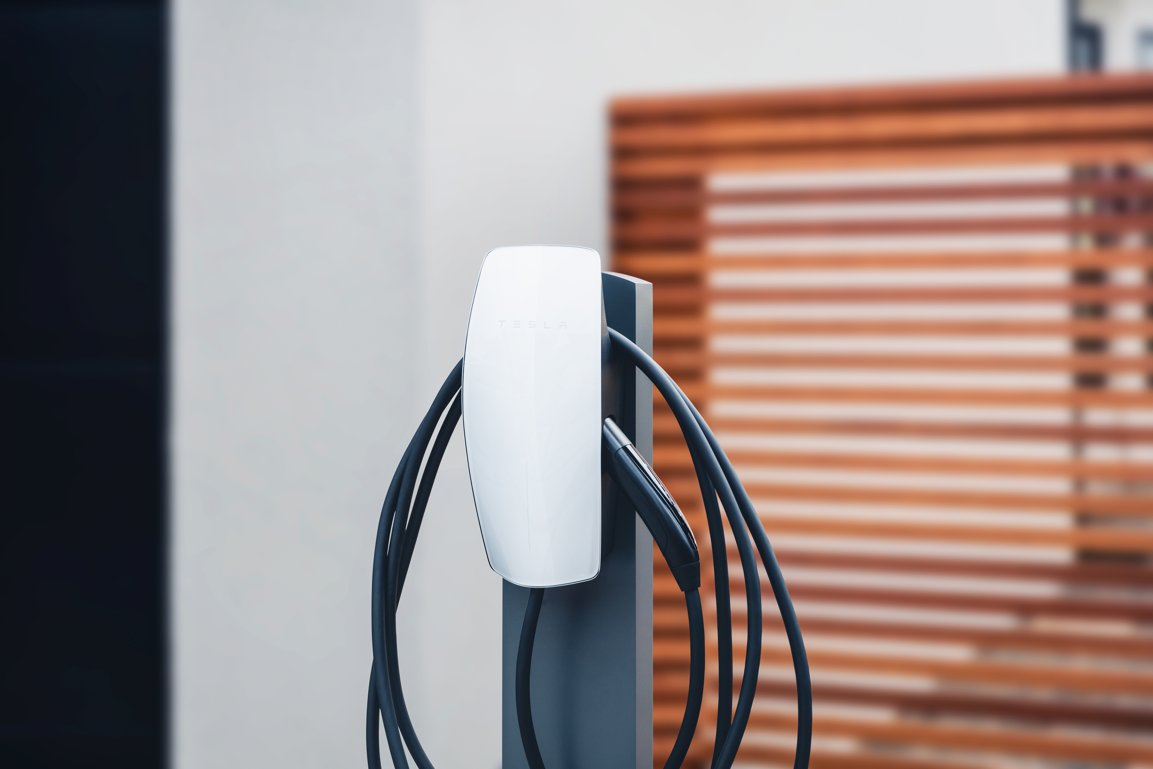 Tesla Wall Connector with its charging cable coiled around it